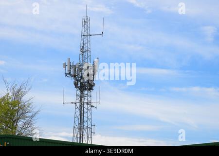Mobilfunk-Kommunikationsturm mit mehreren Antennen und Sendern unter blauem Himmel, die für mobiles Netzwerk, drahtlose Technologie und Konnektivität stehen Stockfoto