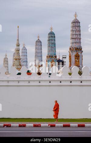 Bangkok, Thailand, 19. November 2025. Ein ruhiger Moment entfaltet sich, während ein Mönch in orangefarbenen Gewändern neben dem berühmten Wat Phra Kaew spaziert. Stockfoto