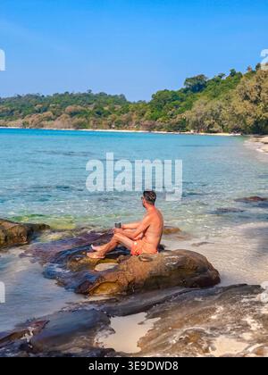 Am Takhian Beach in Koh Kood, Thailand, genießt ein Mann das kristallklare Wasser und die atemberaubende Landschaft. Die friedliche Umgebung lädt zum Entspannen und zur Reflexion ein. Stockfoto