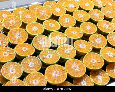 Vollrahmen Hintergrundtextur von frischen grünen Orangen in der Hälfte geschnitten, bereit für gesunden Saft auf einem Obstmarkt gepresst zu werden. Stockfoto