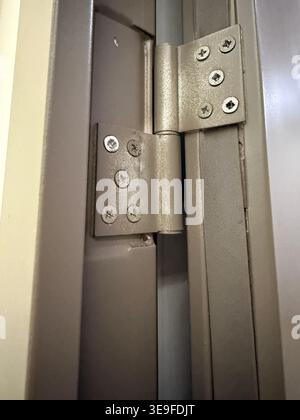 Metallscharnier mit Schrauben am Türrahmen in Nahsicht geeignet für Bauhintergrund. Mobiles Foto Stockfoto