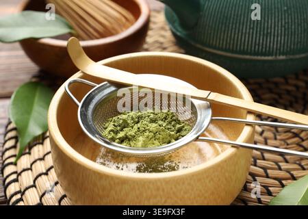 Matcha-Pulver in Schüssel auf Holztisch sieben, Nahaufnahme Stockfoto