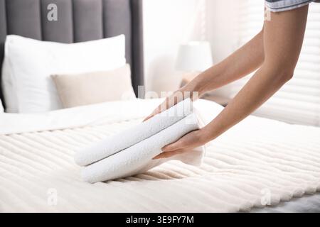 Frau, die Handtücher aus dem Bett nimmt, Nahaufnahme Stockfoto