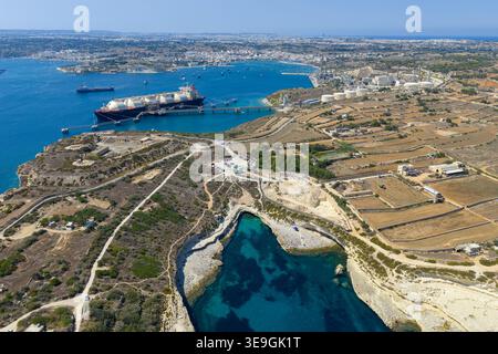 Aus der Vogelperspektive des Delimara Point in der Nähe von Marsaxlokk, mit felsiger Kalksteinküste, türkisfarbenem Einlauf, gewundenen Straßen und Buschland mit einem Schiff vor der Küste. Stockfoto