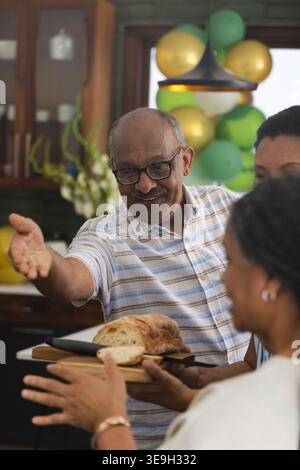 Ranghoher afroamerikanischer Mann mit Reifen Frauen, die lächeln und in die Küche greifen und Brotscheiben anbieten Stockfoto