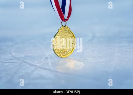 goldene Medaille auf der strukturierten Eisoberfläche im Schnee - Wintersport erfolgreiches Konzept Stockfoto