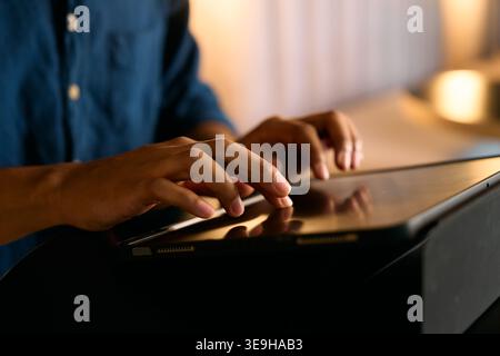 Nahaufnahme eines Geschäftsmannes, der während der Abendstunden im Büro auf einem digitalen Tablet tippt Stockfoto