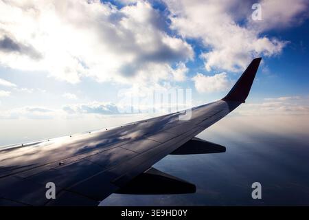Flügelansicht von Boeing 737-800-Flugzeugen, die tagsüber über über Wolken fliegen Stockfoto