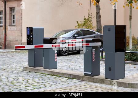 Modernes automatisches Parksperrenarm- und Fahrkartensystem am Eingang des Parkplatzes mit dunkler Limousine im Hintergrund. Stockfoto