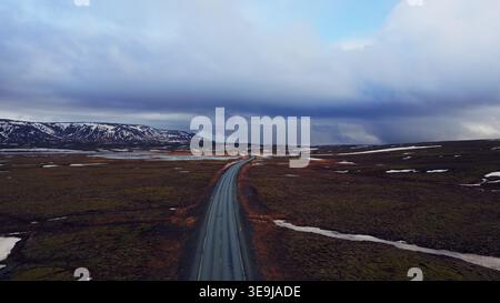 Massive Straßen zwischen verschneiten Bergen und gefrorenen Feldern in island, Drohnenaufnahme der isländischen Straße mit wunderschönen Landschaften. Skandinavische malerische Route mit Hügeln, Winterlandschaft. Stockfoto