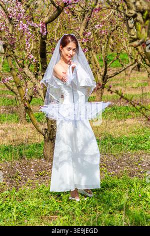 Braut in weißem Kleid und Schleier im Frühlingsgarten Stockfoto