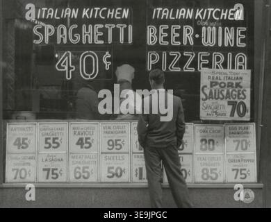 Historisches Foto mit dem Titel Italian Kitchen Storefront, New York City, das einen Mann zeigt, der die Menüpreise in einem Restaurant liest, während ein Koch im Inneren das Essen zubereitete. Foto von Angelo Rizzuto, September 1956 Stockfoto