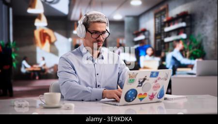 Lerner Mit Fokussiertem Grafikdesign Mit Laptop In Lebendiger Coffee Shop-Umgebung Stockfoto
