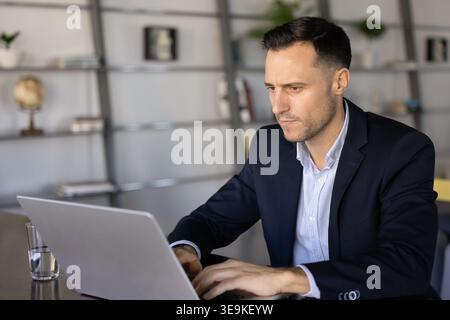 Fokussierter Geschäftsmann, der am Schreibtisch am Laptop arbeitet Stockfoto