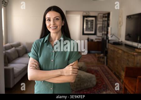 Selbstbewusste Frau, die zu Hause mit gekreuzten Armen steht Stockfoto