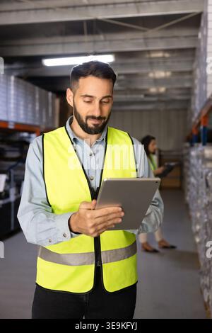 Männlicher Angestellter, der den Bestand auf einem digitalen Tablet im Industrielager überprüft Stockfoto