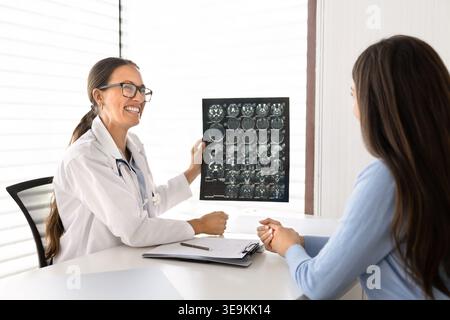 Lächelnder Arzt zeigt Röntgenaufnahme bei Patientin Stockfoto