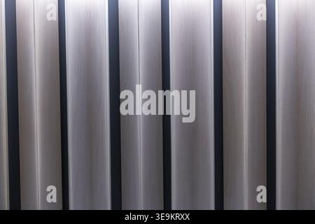 Abstrakter Hintergrund mit vertikalem Linienmuster mit metallischer Textur, die Licht und Schatten reflektiert und eine ruhige und moderne industrielle Atmosphäre schafft Stockfoto