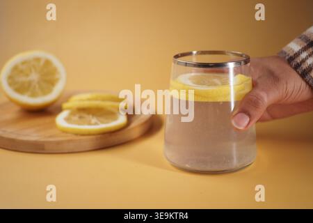 Zitronenwasser serviert in einem Glas auf gelbem Hintergrund Stockfoto