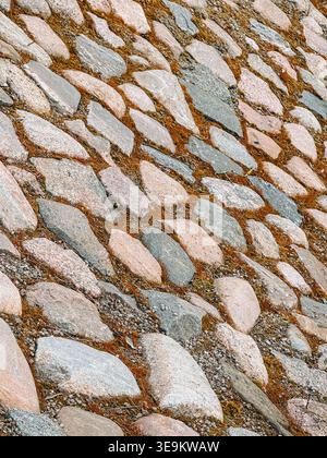 Hochauflösender Pflastersteinpflaster mit Moos und Kies, die ein organisches strukturiertes Muster bilden. Ideal als natürlicher Hintergrund für Design und Architektur Stockfoto