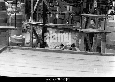 Slawjansk, 1950er Jahre AIZ-Werk. Ein einzigartiges historisches Schwarzweiß-Archivfoto, das die große Speicherinfrastruktur in der Produktionswerkstatt beschreibt. Hunderte von fertigen Keramikisolatoren in verschiedenen Formen und Größen sind ordentlich auf mehrstufigen Metallregalen angeordnet. Diese industrielle Landschaft ohne Menschen veranschaulicht perfekt die beeindruckenden Mengen der sowjetischen Fertigung, der Arbeitsraumorganisation und der technischen Ästhetik der Mitte des zwanzigsten Jahrhunderts und spiegelt einen friedlichen Donbass wider. Stockfoto
