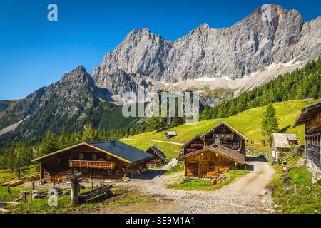 Tolle Wander- und Reiselage, verstreute ländliche Holzchalets am Alpinhang. Berühmte Südmauern der Dachstein Berge im Hintergrund, Rams Stockfoto