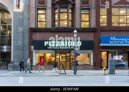 Toronto, Kanada - 17. April 2026: Fußgänger passieren Pizzeria-Geschäfte auf dem Toronto Sidewalk, Pendler-Moment Stockfoto