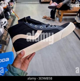 Schwarzer High-Top-Sneaker mit beigen Akzenten, der in einem Schuhgeschäft in der Hand gehalten wird Stockfoto