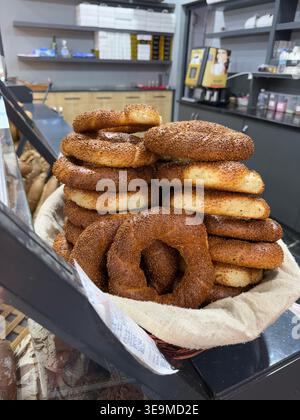 Türkische Simit-Bagels, gestapelt in einem Korb auf einem Ladentisch, perfekt für Backwaren Hintergrund. Mobiles Foto Stockfoto