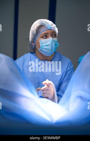 Kaukasische Chirurgin im Operationssaal mit chirurgischem Instrument Stockfoto