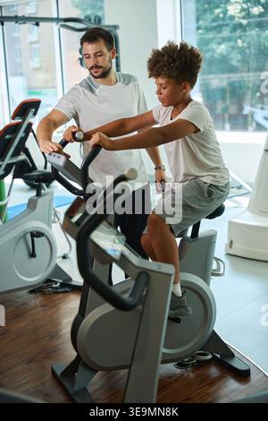 Zwei junge Männer konzentrierten sich während des Trainings am Tag auf das Radfahren im Fitnessstudio Stockfoto