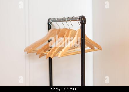 Leere Holzbügel hängen an einem Regal im hellen Kleiderschrank. Stockfoto