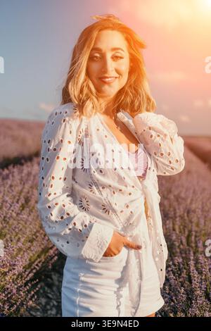 Frau Lavendel Sonnenuntergang schöne junge Frau lächelt, während sie in einem blühenden lila Lavendelfeld während Sonnenuntergang goldene Stunde steht Stockfoto