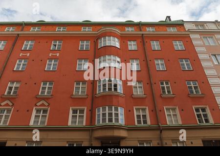Rote Backsteingebäude mit Fensterreihen und Balkonen bei Sommertageslicht. Stockfoto