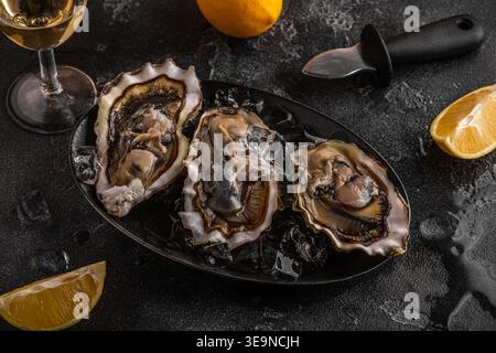 Frische Austern aus nächster Nähe auf Eis serviert mit Zitrone und Wein. Gesunde Meeresfrüchte, Gourmetgerichte. Stockfoto