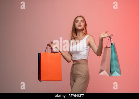 Junge Frau, die gerne shoppt, bunte Taschen trägt, glücklich und zufrieden mit Einkäufen ist Stockfoto