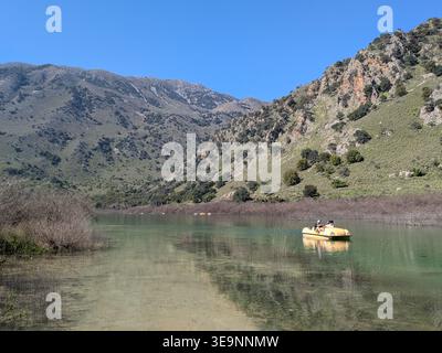 Zwei Personen im Tretboot auf dem Kournas-See mit bergigem Hintergrund an sonnigem Tag Stockfoto