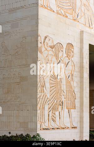 Nahaufnahme einer modernen Steinfassade mit komplizierten Basreliefschnitzereien von menschlichen Figuren im alten ägyptischen Stil in Wafi City, Dubai. Stockfoto