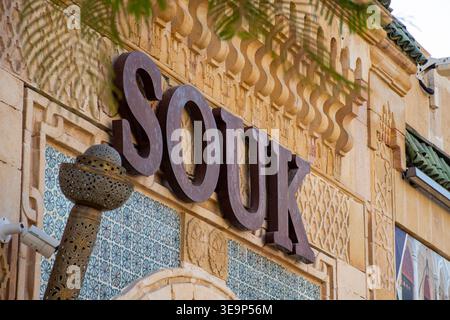 Großes 3D-Metall-„SOUK“-Schild an der verzierten Fassade eines traditionellen Dubai-Gebäudes mit islamischen Steindetails und geometrischen Fliesen. Stockfoto
