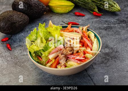 Appetitlicher Nudelsalat mit Thunfisch und Gemüse in einer cremigen Sauce. Die Top-Down-Ansicht auf dunklem Hintergrund hebt frische rote, grüne und beige Farben hervor. P Stockfoto
