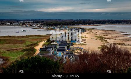 Eine malerische Küstenlandschaft mit lebhaften Strandhütten, einem Sandweg und ruhigem Wasser. Das Bild fängt den Charme des Lebens am Meer und der nat ein Stockfoto