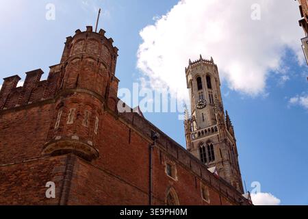 Sonniger Blick auf den Glockenturm von Brügge, der sich über dem historischen Marktplatz erhebt und mittelalterliche flämische Architektur unter einem klaren blauen Himmel zeigt, Brügge, We Stockfoto
