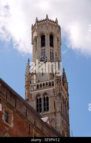 Sonniger Blick auf den Glockenturm von Brügge, der sich über dem historischen Marktplatz erhebt und mittelalterliche flämische Architektur unter einem klaren blauen Himmel zeigt, Brügge, We Stockfoto