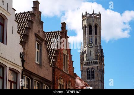 Sonniger Blick auf den Glockenturm von Brügge, der sich über dem historischen Marktplatz erhebt und mittelalterliche flämische Architektur unter einem klaren blauen Himmel zeigt, Brügge, We Stockfoto