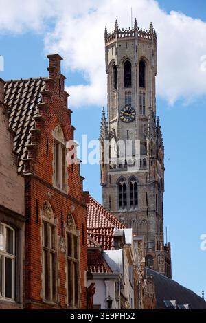 Sonniger Blick auf den Glockenturm von Brügge, der sich über dem historischen Marktplatz erhebt und mittelalterliche flämische Architektur unter einem klaren blauen Himmel zeigt, Brügge, We Stockfoto