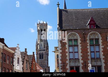 Sonniger Blick auf den Glockenturm von Brügge, der sich über dem historischen Marktplatz erhebt und mittelalterliche flämische Architektur unter einem klaren blauen Himmel zeigt, Brügge, We Stockfoto