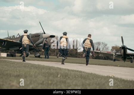 Drei Piloten der RAF kämpfen in Sywell über den Asphalt in Richtung Spitfire und Hurrikan in einer Nachstellung der Schlacht um Großbritannien im Zweiten Weltkrieg Stockfoto