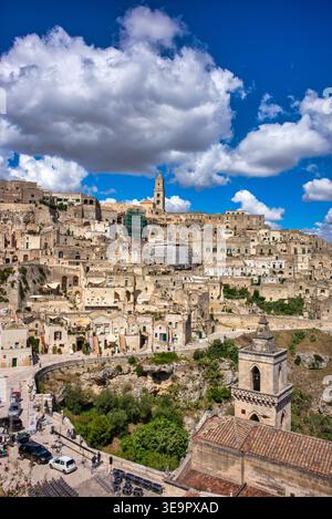 Die alten Steinhäuser von Sassi di Matera in Italien. Die Gebäude liegen auf Hügeln unter einem hellblauen Himmel mit Wolken. Stockfoto