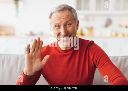 Ein Senior-Mann begrüßt tagsüber im Wohnzimmer mit einem Lächeln Stockfoto