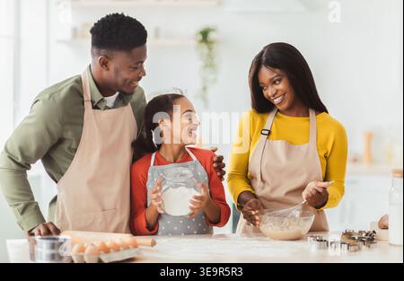 Die Familie genießt es, gemeinsam in einer Küche zu backen, während sie Lächeln und Lachen teilt Stockfoto